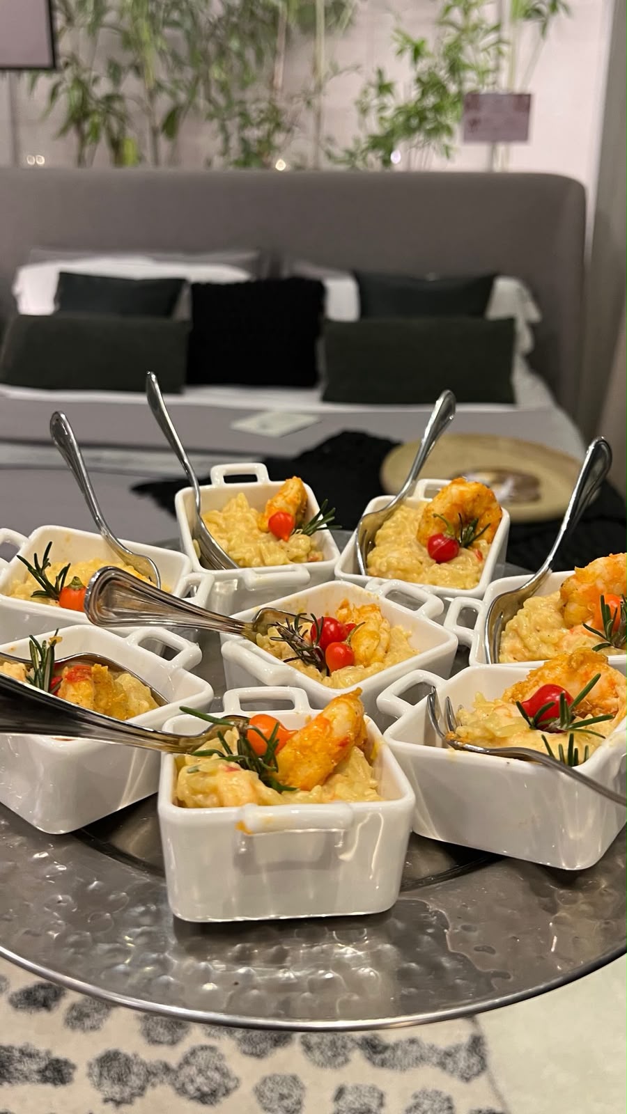 risotos com camarão servidos em minirecipientes brancos com colheres sobre uma bandeja prateada, com uma cama 